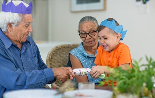 boy and grandparents wearing christmas crowns pulling christmas cracker