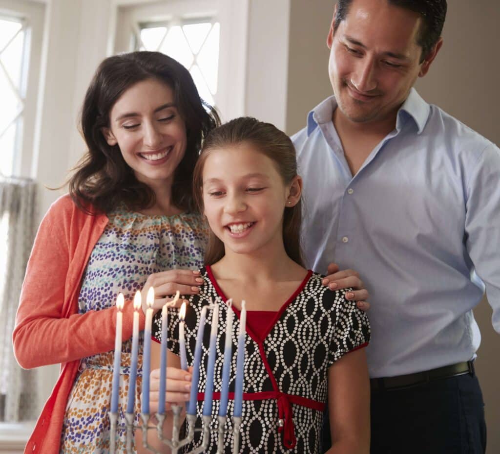 Family lighting a menora for Hanukkah